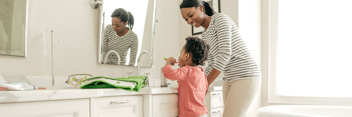 Adulte regardant un enfant se brosser les dents au lavabo
