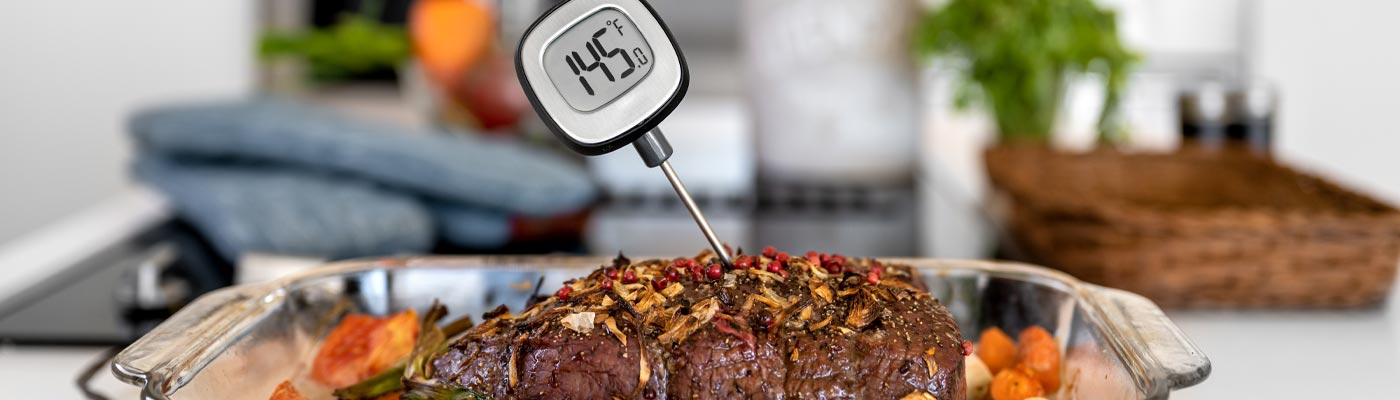 Thermomètre à viande avec des chiffres de 145 degrés Fahrenheit insérés dans de la viande cuite.