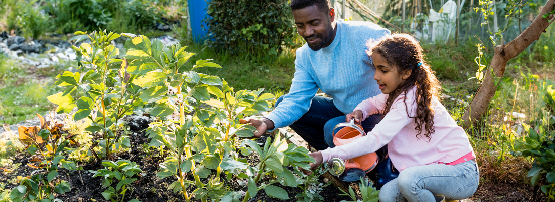 adult and child kneeling at a garden