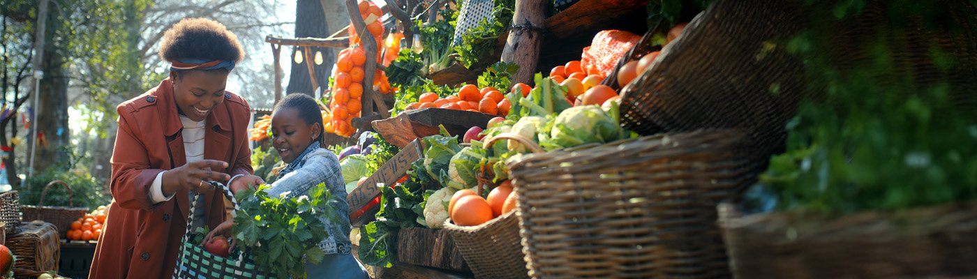 Adult and child filling a grocery bag with fresh vegetables