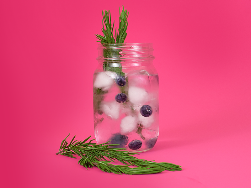 jar of water with blueberries and rosemary stems added
