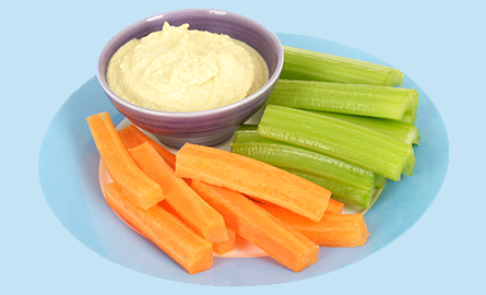 Hummus in a bowl with sliced carrots and celery